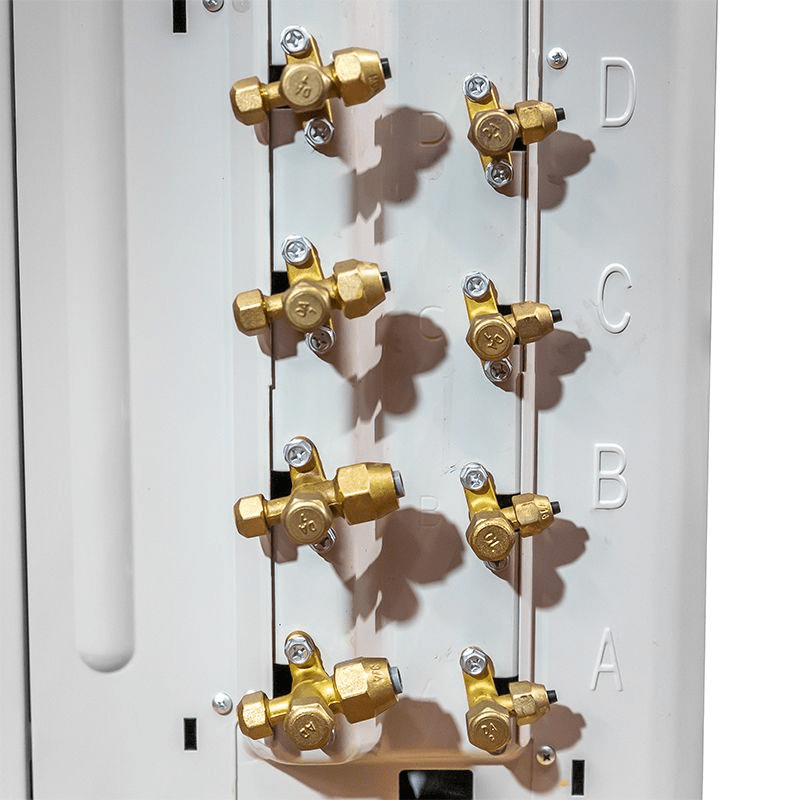 A close-up view of the brass refrigerant line connections, or service valves, on a multi-zone air conditioner condenser unit, labeled with the letters A, B, C, and D